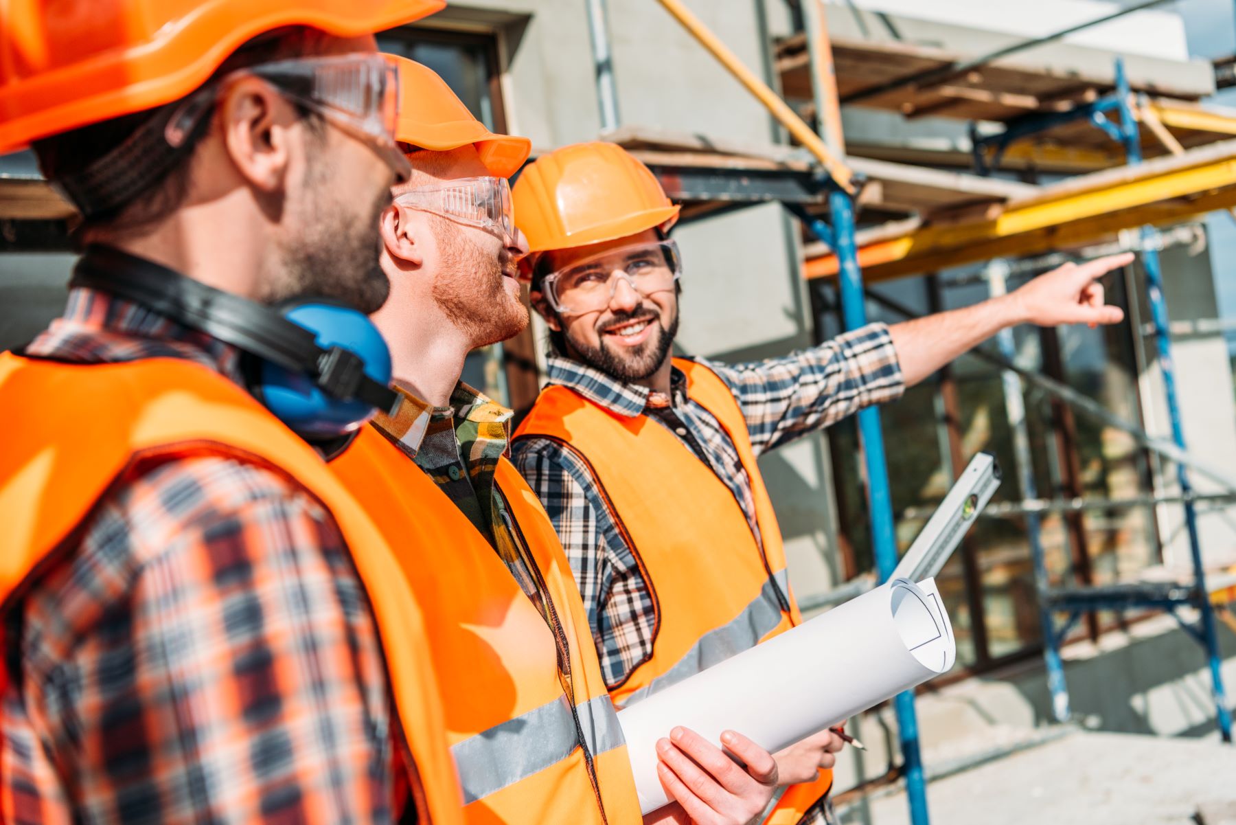 Construction workers in safety gear on a job site discussing plans, highlighting safety training and workplace safety practices