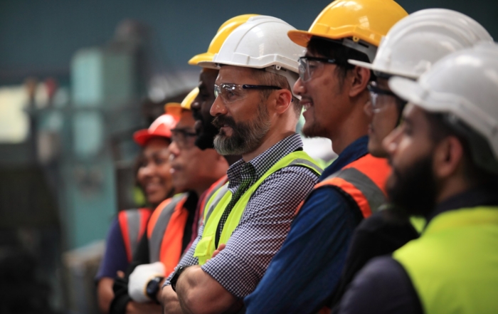 Industrial workers wearing safety helmets and reflective vests during a workplace safety briefing, emphasizing the importance of safety protocols in industrial and construction settings.