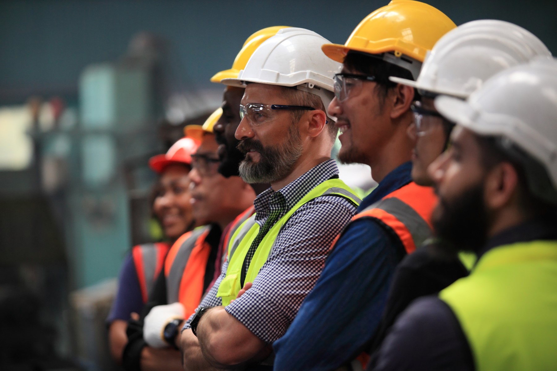 Industrial workers wearing safety helmets and reflective vests during a workplace safety briefing, emphasizing the importance of safety protocols in industrial and construction settings.